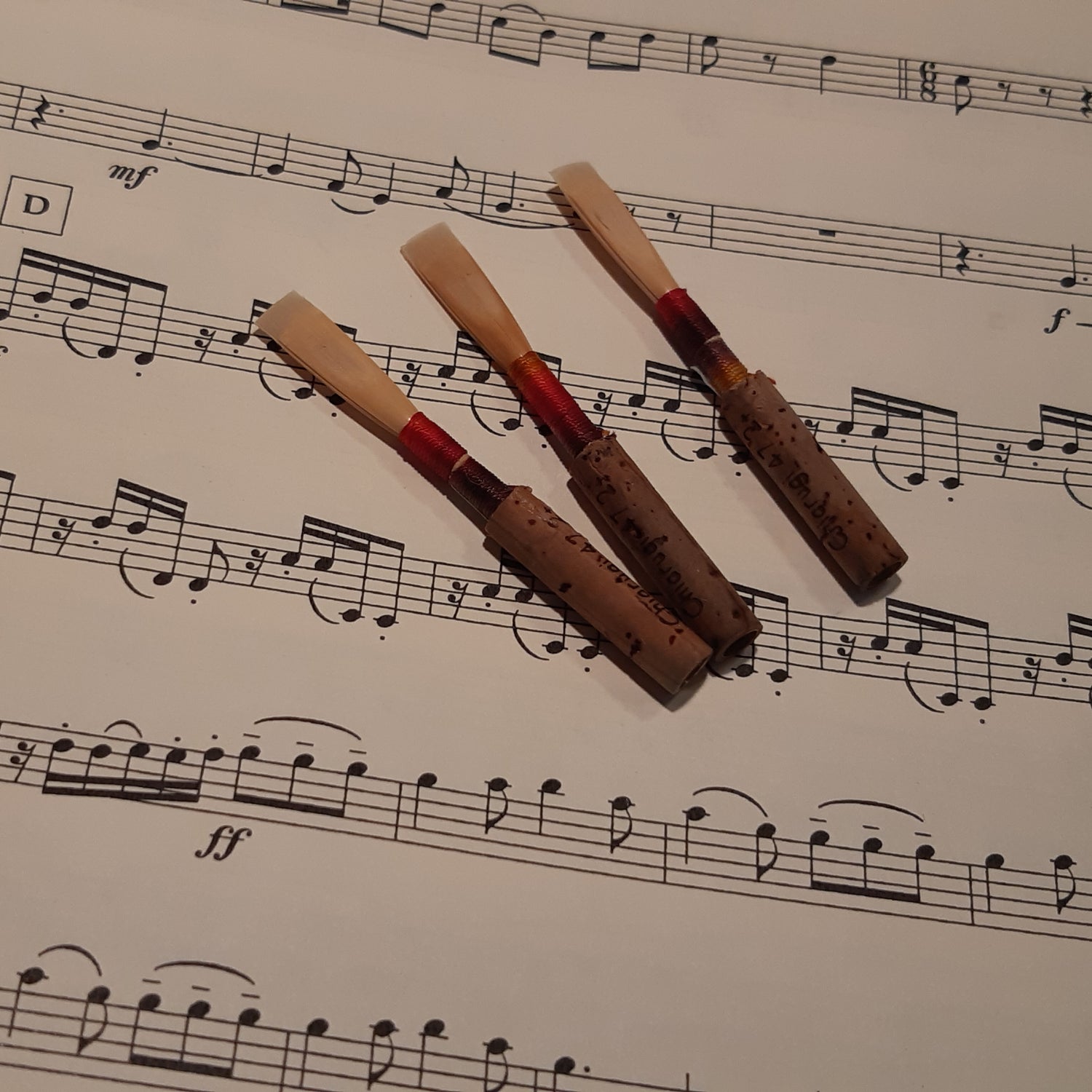 three oboe reeds with sheet music in the background